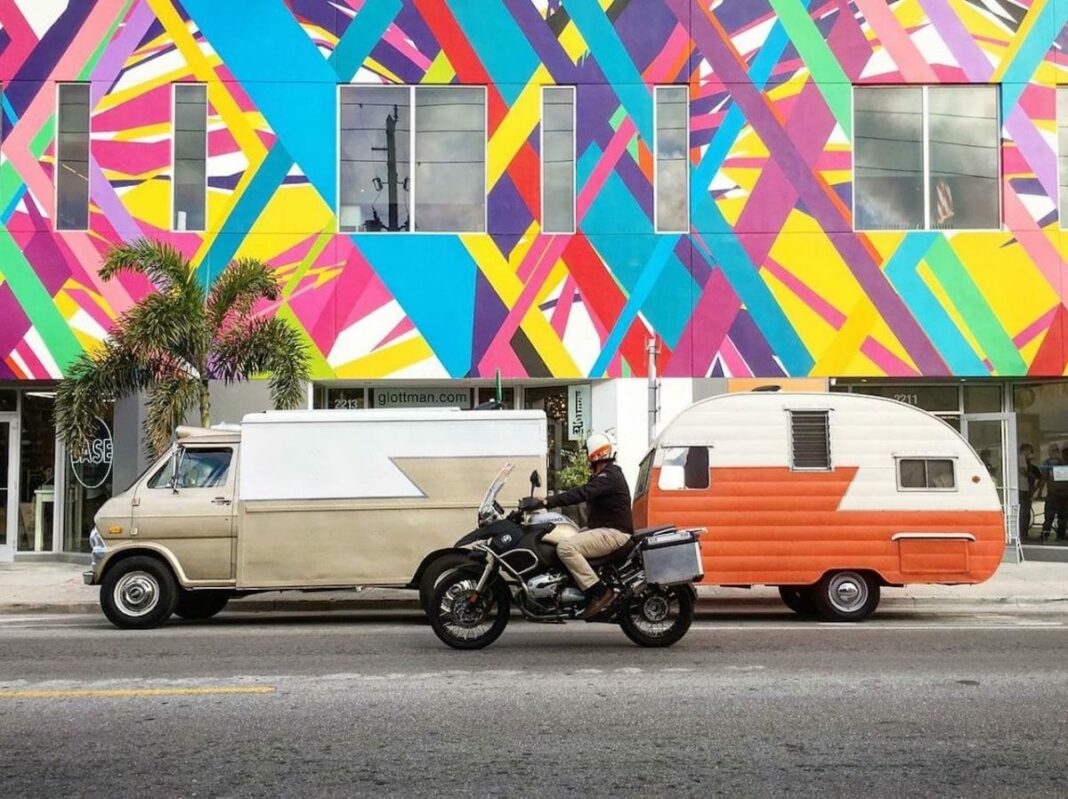 building with mural painted on it and man on motorcycle looking and driving past it