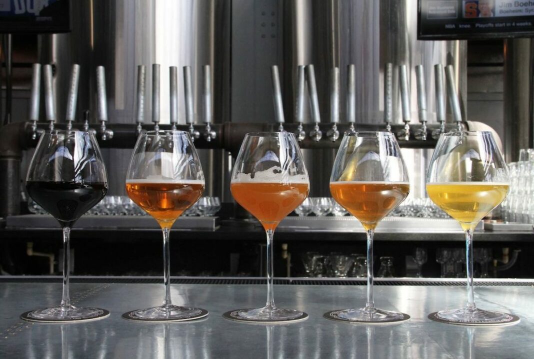 wine glasses full of beer on bartop with stainless steel taps in background