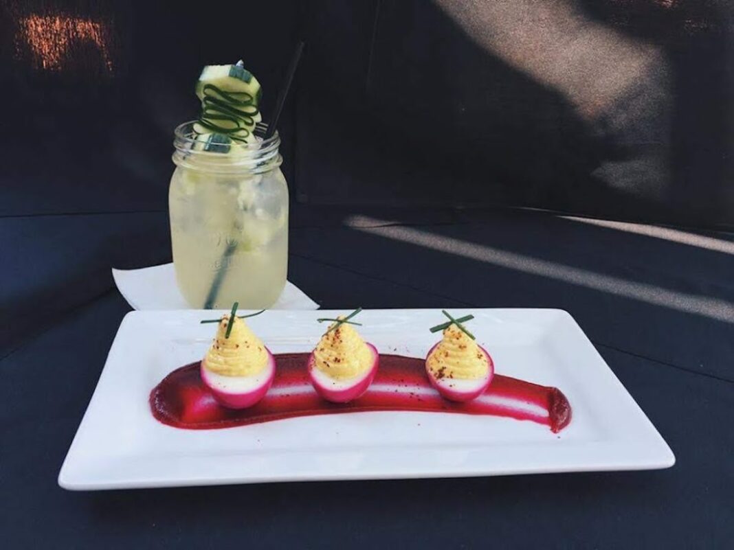 white plate with red and yellow food on it and refreshing drink in background
