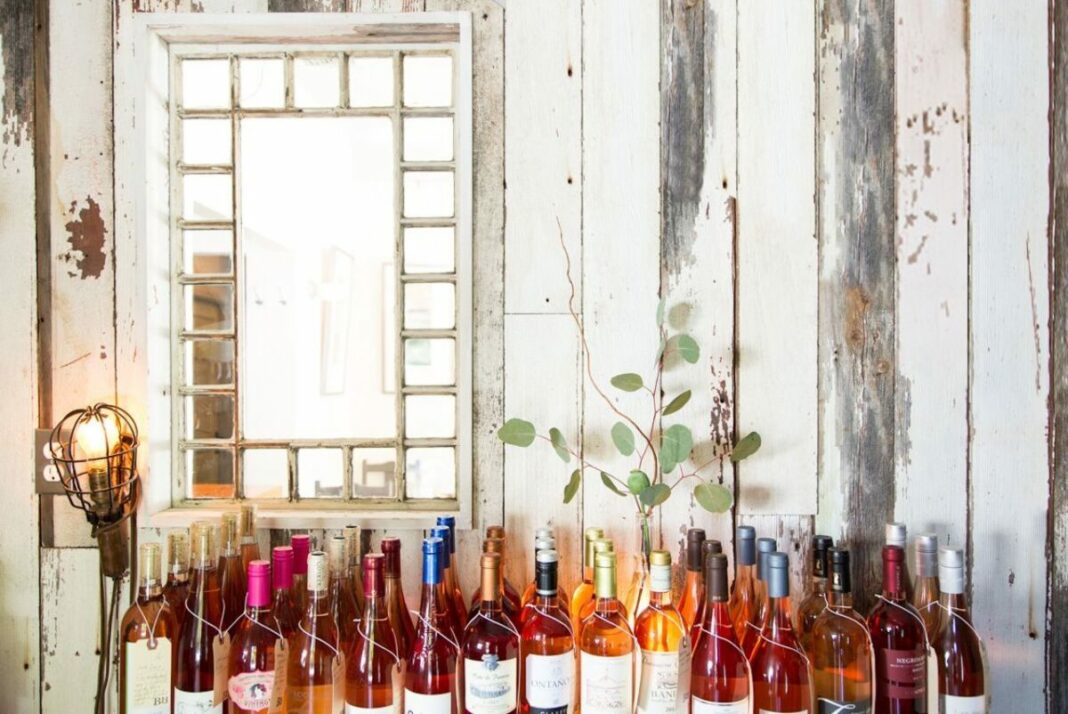 white wooden wall with window and wine bottles sitting in front of it