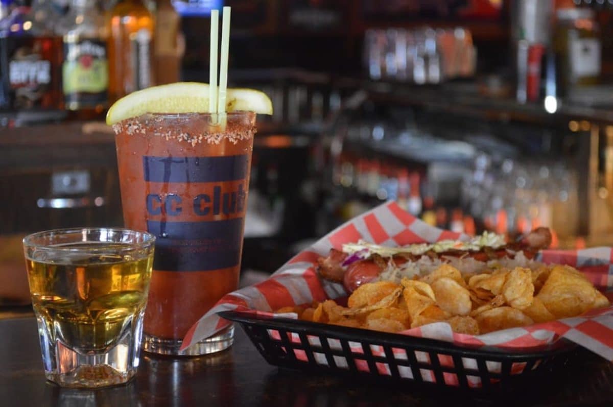 basket of chips, hot dog, and bloody mary and shot of whiskey on bar top
