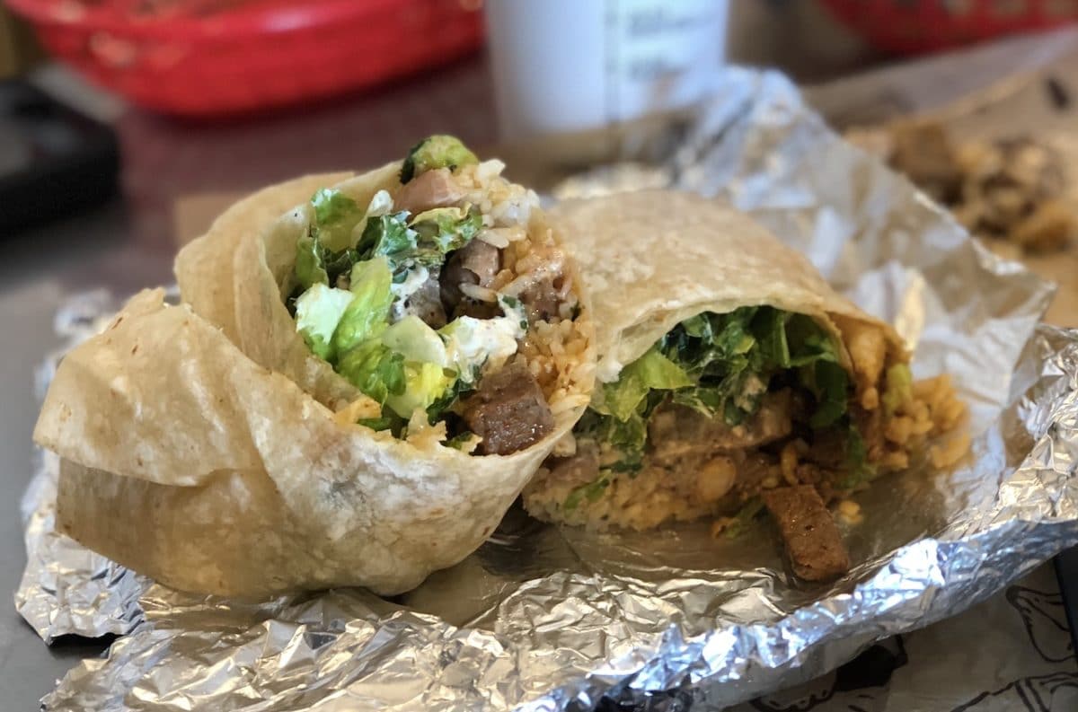 close up of steak burrito cut in half on aluminum foil
