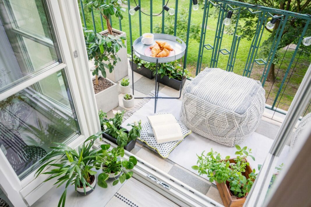 Top view of a garden on balcony with plants, pouf, and a table with breakfast