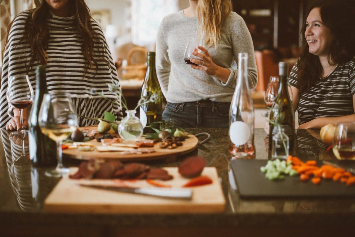 women gathered around dinner table eating and drinking wine