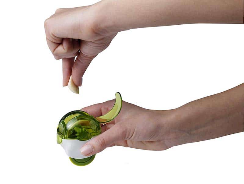 person putting garlic glove into garlic chopper