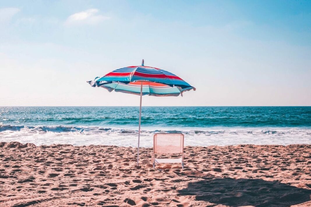 beach chair and umbrella on sand looking out to water
