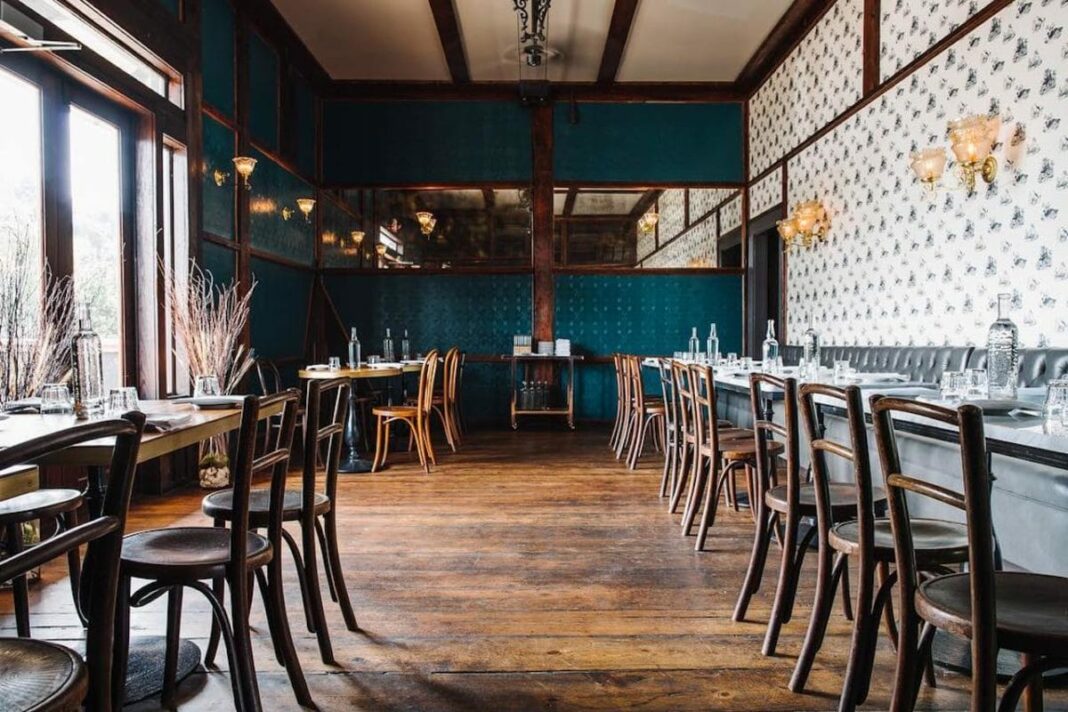dining area with brown tables and chairs with lights above and wallpaper on walls