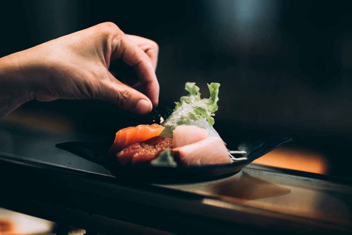 person's hand putting salt on top of omakase