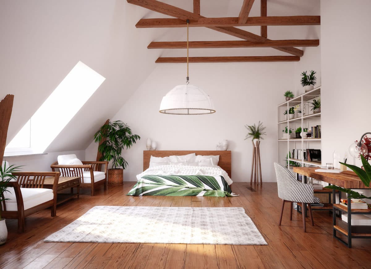 studio with bed, brown wooden beams on ceiling, and desk 