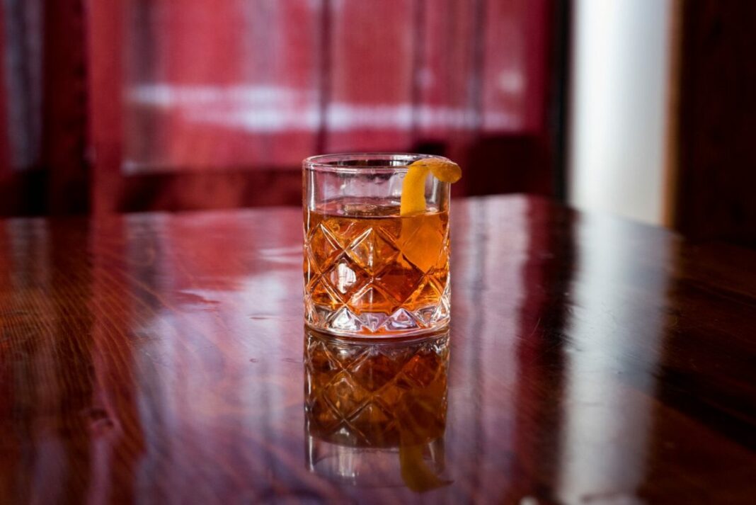 cocktail on table by itself with pink color in background