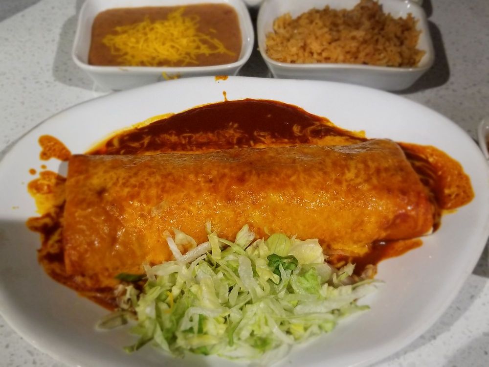 large burrito on white plate covered in red sauce and cheese