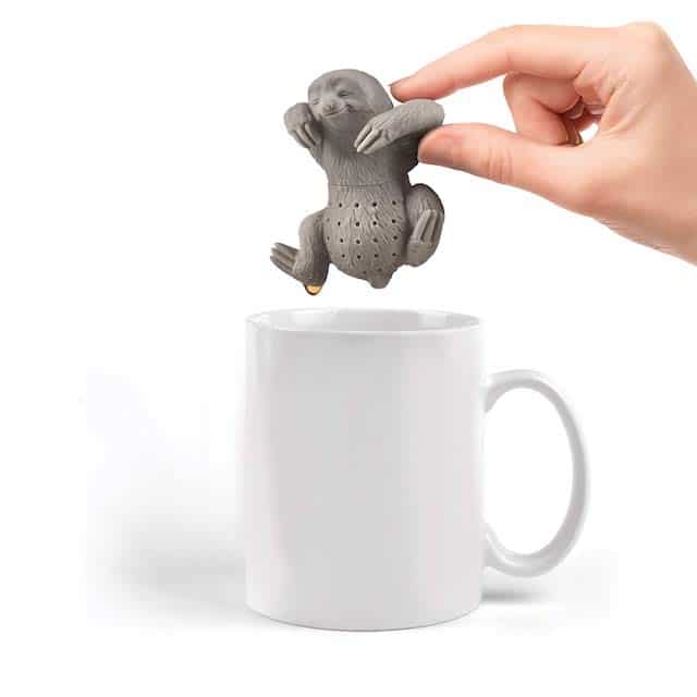person putting sloth tea infuser into white mug