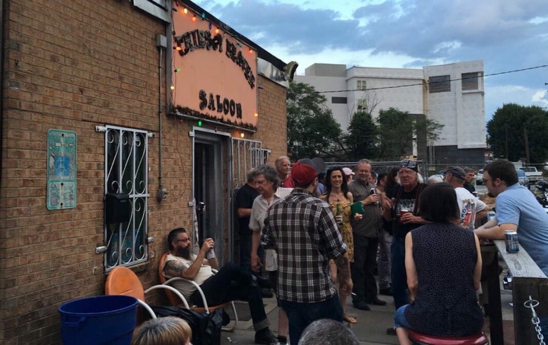 exterior of dive bar with people drinking and talking on patio