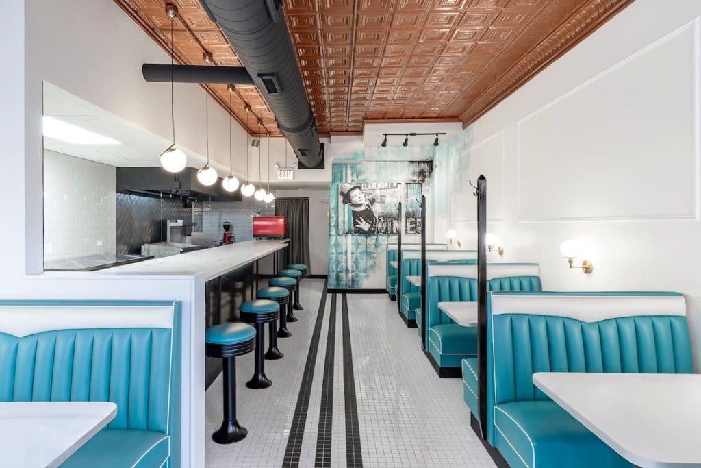 empty diner with white walls, blue seats, and bright lights