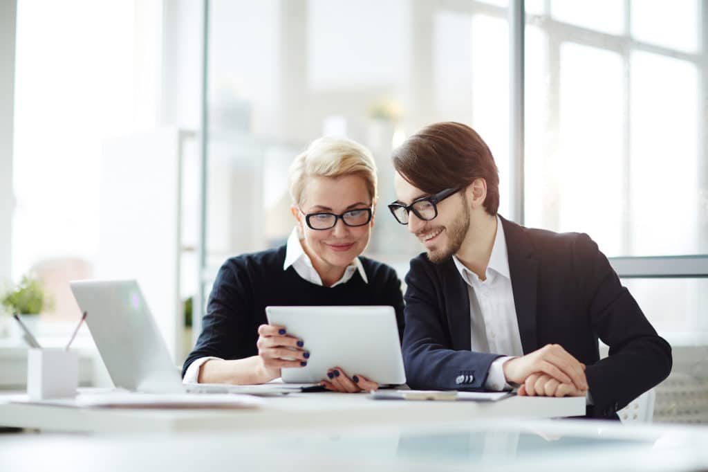 two business people sitting side by side and reading