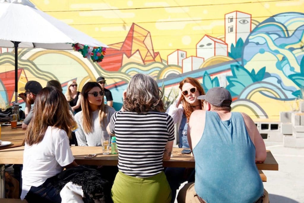 people sitting at picnic table outside on brewery patio