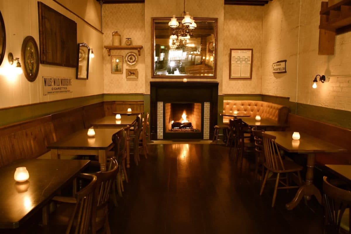 room in bar with fireplace and candles on each wooden table 