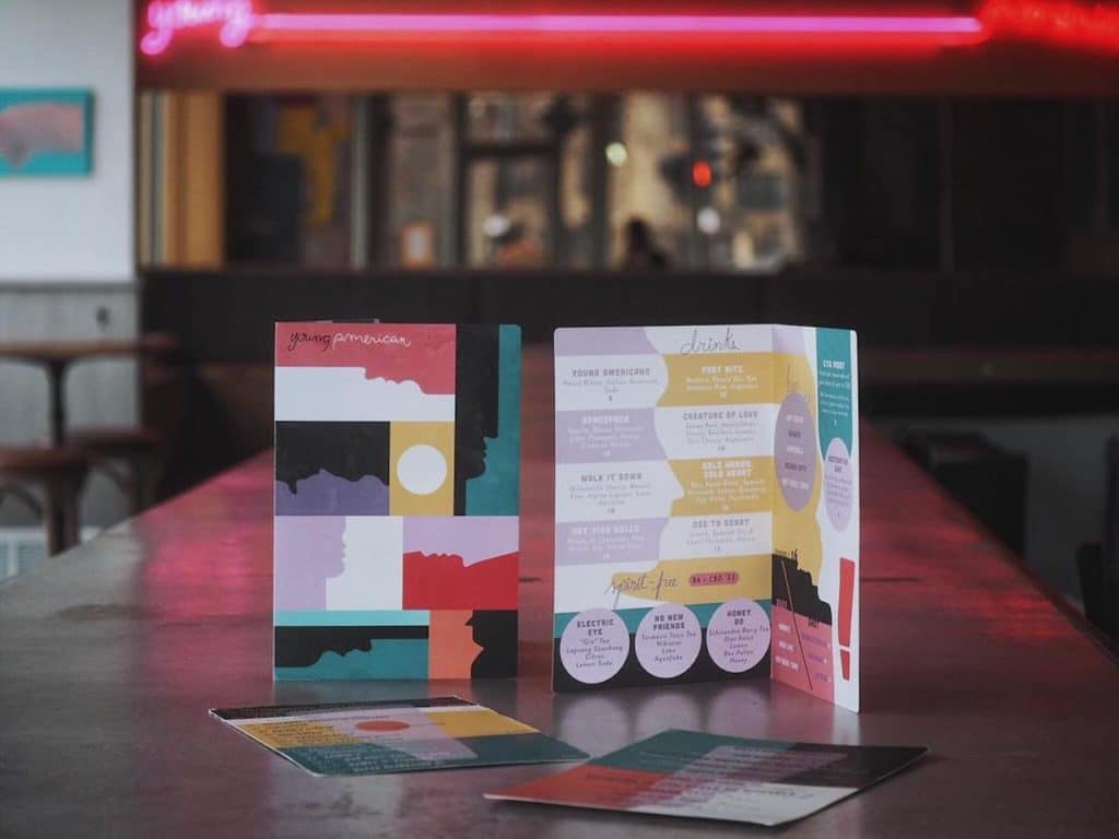 colorful menu standing up on table with pink light in background