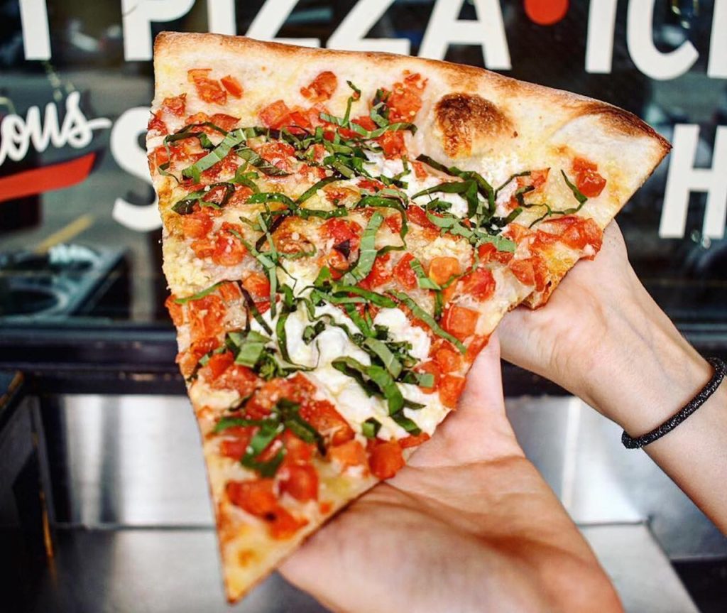 up close picture of slice of pizza with red and green toppings