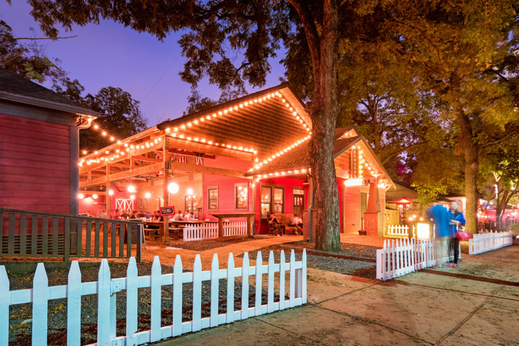 outdoor seating at large bar with string lights and picket fenceon rainey street