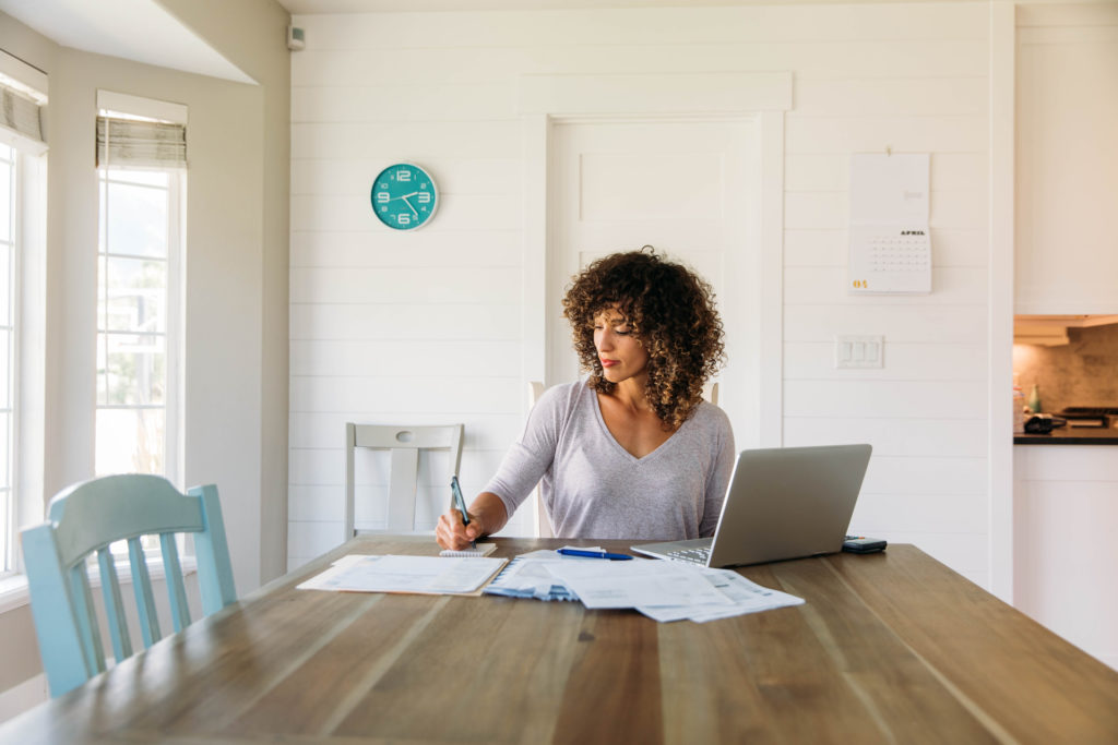 woman sits at table writing proof of income letter 