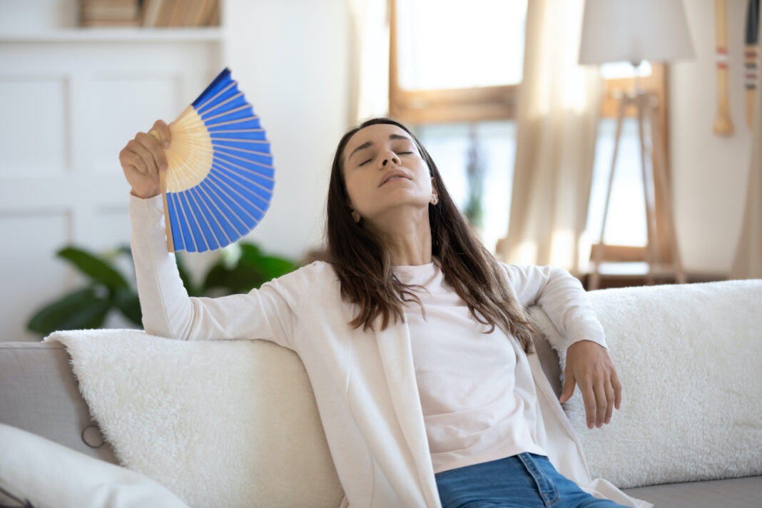 woman uses fan to cool down