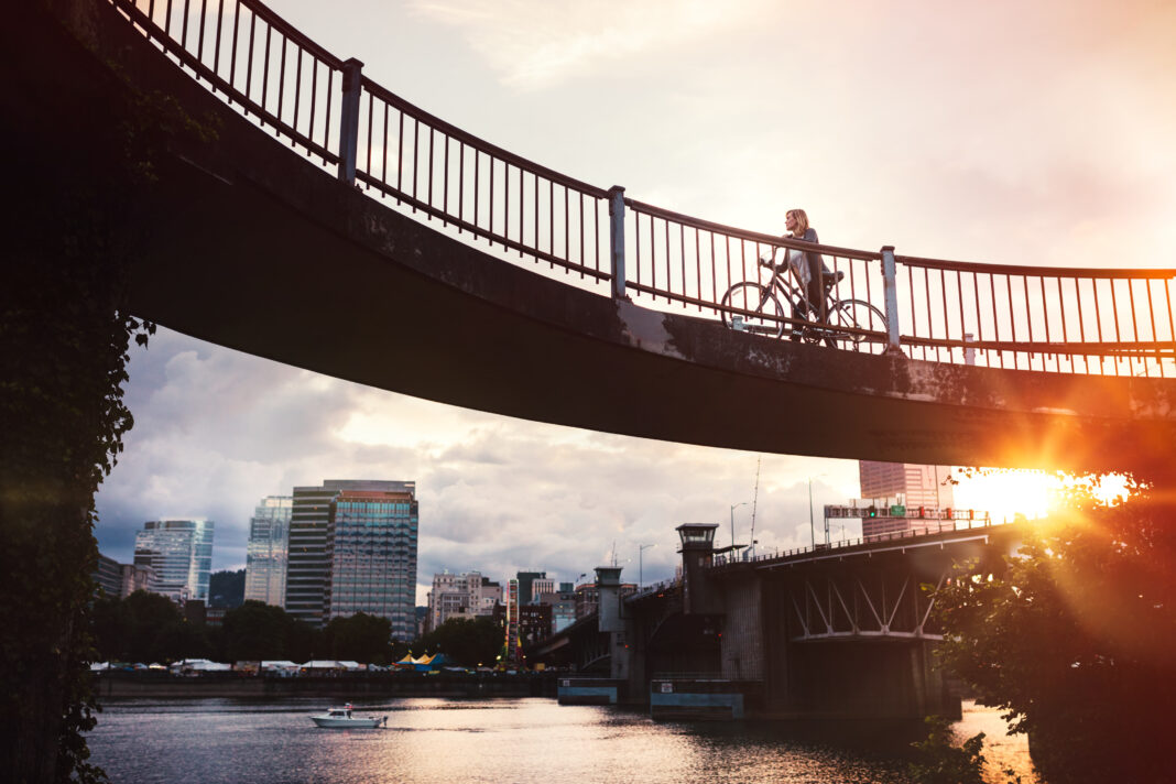 Woman rides a bike over a bridge in the Buckman neighborhood of Portland, OR