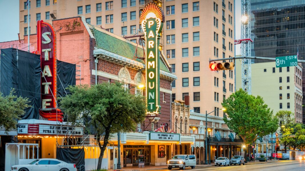 Theater marquees and cars on Congress Avenue in downtown Austin, Texas, USA at dawn.
