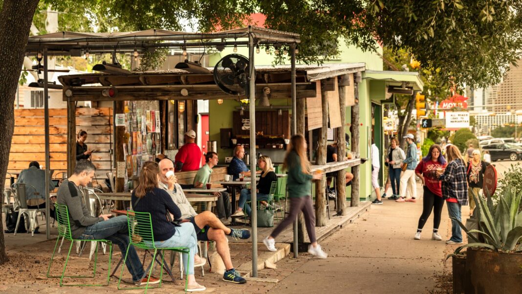 People walk along the trendy South Congress Street colourful shops and cool restaurants in Austin Texas USA.