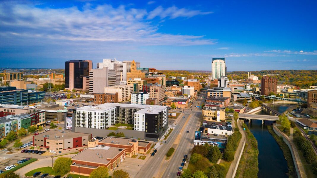 Downtown Rochester skyline aerial view during early Autumn, with a blue skyline with clouds in the background.