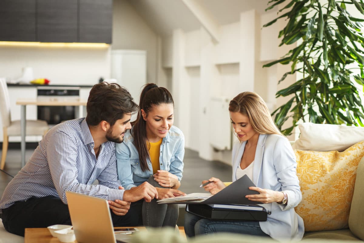 woman showing a man and a woman paperwork in new apartment